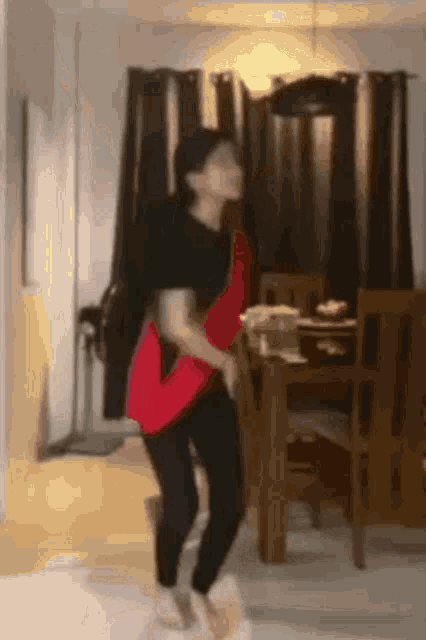 a woman is dancing in a living room while holding a red purse .