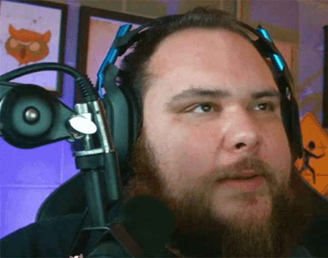 a man with a beard wears headphones and a microphone