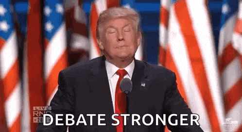 donald trump is giving a speech in front of a microphone while standing in front of a crowd of american flags .