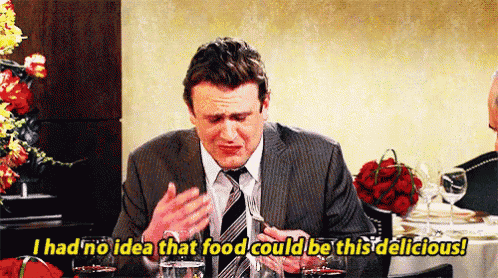 a man in a suit and tie is sitting at a table with a glass of wine and a fork in his hand .