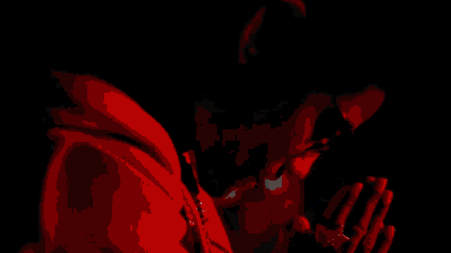 a man in a red hoodie with his hands folded in prayer