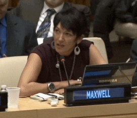 a woman sits at a table with a sign that says maxwell on it