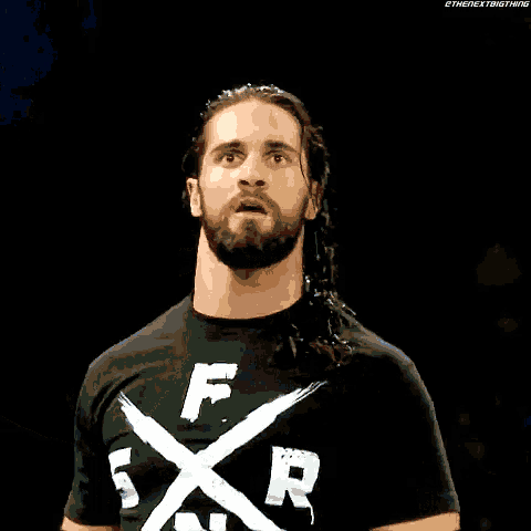 a man with long hair and a beard is wearing a black shirt with the letter r on it