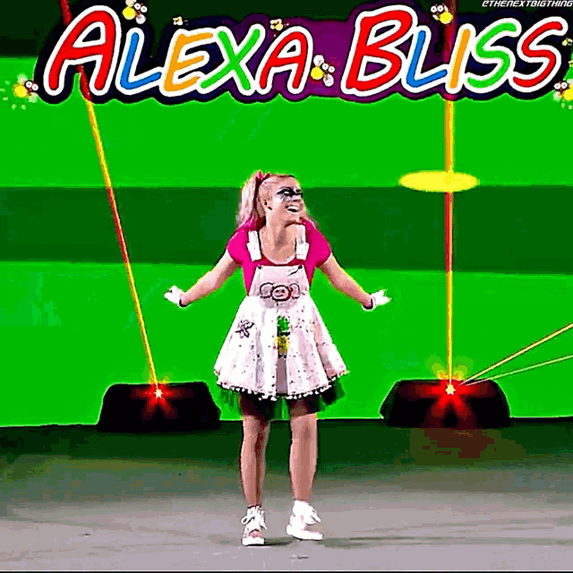 a woman in a pink dress stands in front of a green screen that says alexa bliss