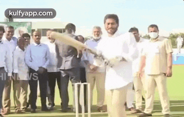 a man is holding a cricket bat in front of a crowd of people .
