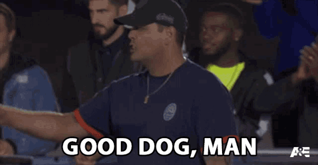 a man in a baseball cap is standing in a crowd and says good dog man