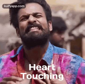 a man with a beard is making a funny face while holding his chest and says `` heart touching '' .