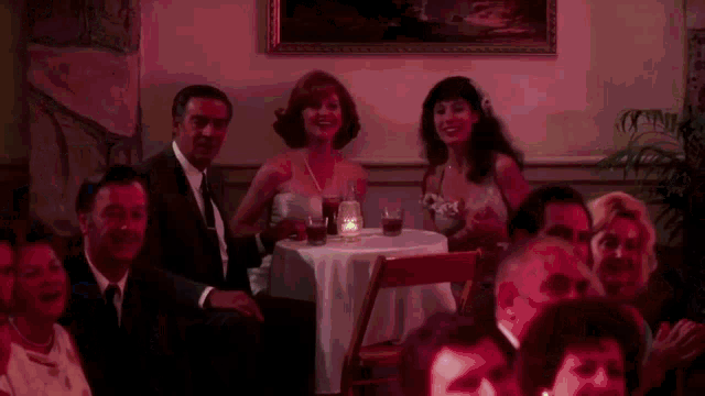 a group of people are sitting at a table with a candle on it