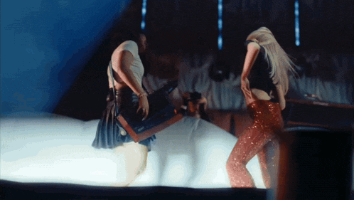 two women are dancing on a stage and one of them is holding a box