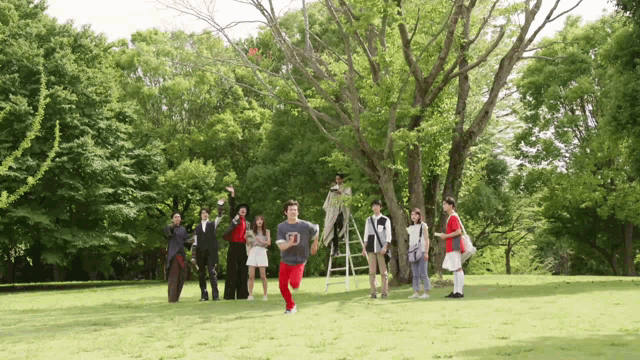 a group of people are standing in a park and one of them is wearing a shirt that says d.