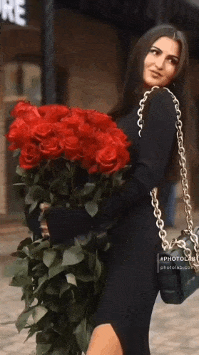 a woman holding a large bouquet of red roses