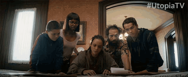 a group of people are looking at a piece of paper with the hashtag utopiatv on the bottom
