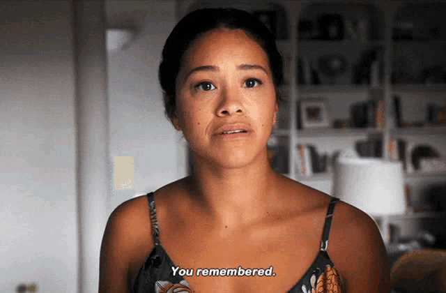a woman in a bra says " you remembered " in front of a bookshelf