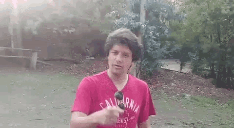 a man wearing a pink california t-shirt is pointing at the camera .