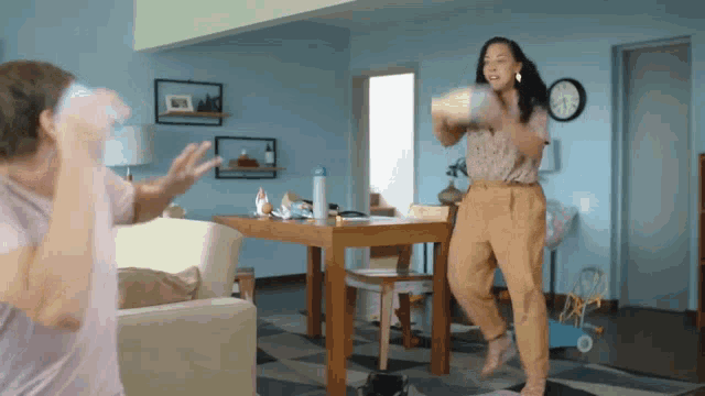 two women are playing a game in a living room with a clock in the background
