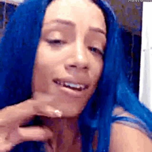 a woman with blue hair is making a funny face while looking at the camera .