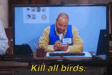 a man in an animal control uniform is sitting at a desk on a television screen