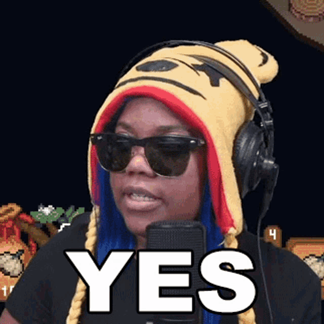 a woman wearing a winnie the pooh hat and sunglasses says yes in front of a microphone