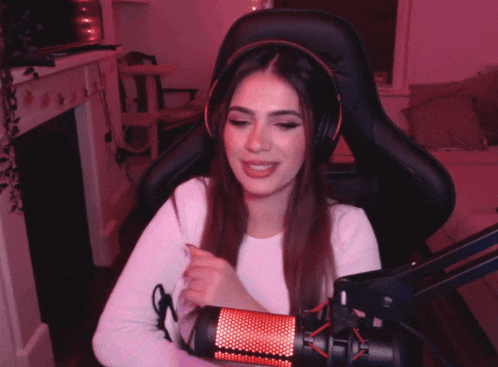 a woman wearing headphones is sitting in front of a microphone and smiling