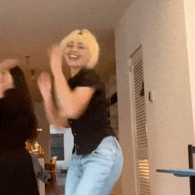 two women are dancing together in a living room .