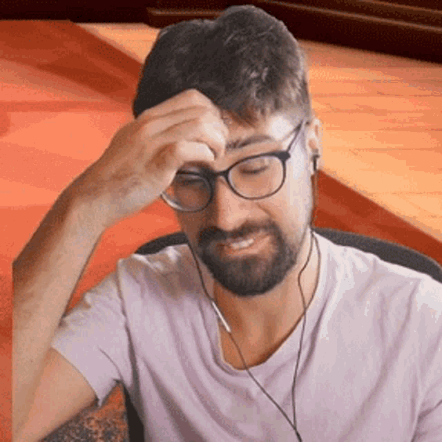 a man wearing glasses and ear buds holds his head