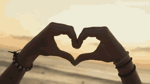 a person making a heart shape with their hands in front of a spinnin ' tv banner