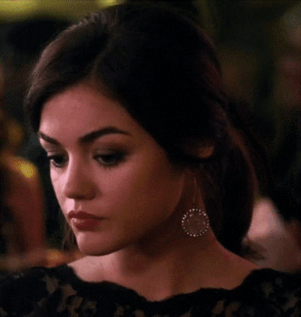 a close up of a woman wearing earrings and a black dress