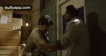 two men are standing next to each other in a room and fighting .