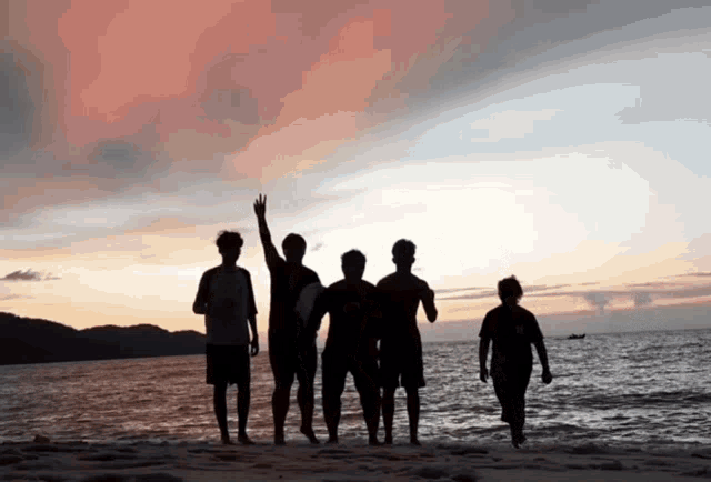a group of people standing on a beach with one wearing a shirt that says ' a ' on it