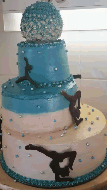 a blue and white cake with a gymnast on top
