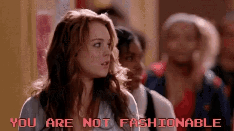 a woman is standing in front of a group of people and the words you are not fashionable are displayed on the screen .