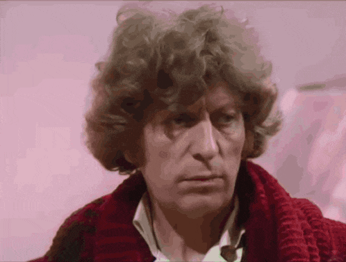 a man with curly hair is wearing a red scarf around his neck .
