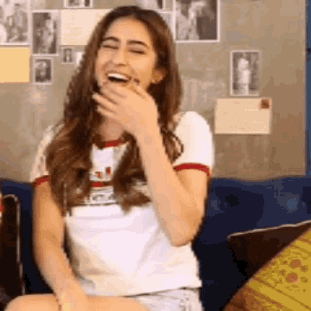 a woman is sitting on a couch covering her mouth with her hand .