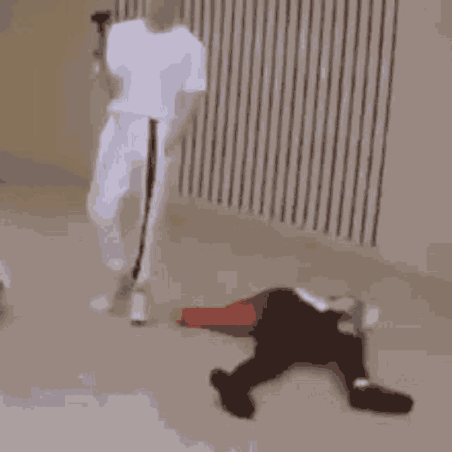 a man in a white shirt is standing next to a mannequin laying on the floor .
