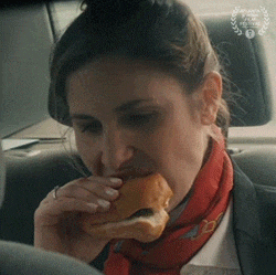 a woman is sitting in a car eating a sandwich