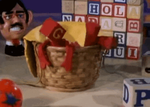 a basket filled with alphabet blocks is on a table next to a stack of alphabet blocks .