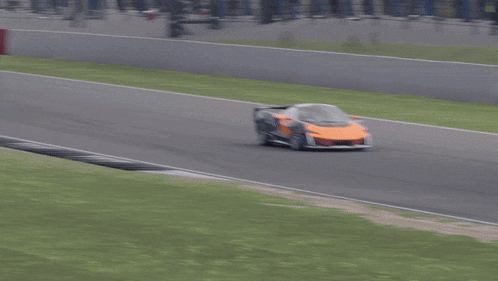 a race car is driving down a track with a red building in the background that says coca-cola