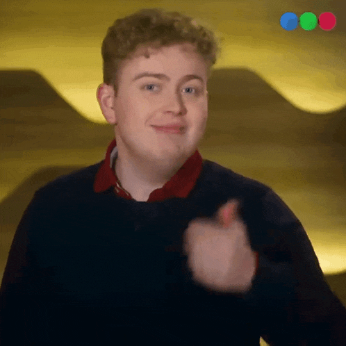 a young man is giving a thumbs up in front of a yellow background