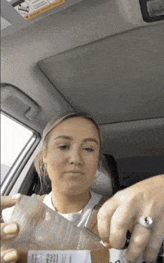 a woman is sitting in a car holding a bag with a sticker on it that says " do not leave child in car "