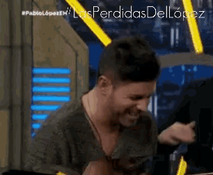 a man is laughing in front of a screen that says las perdidas dellopez