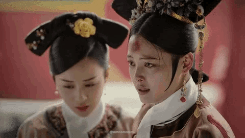 two women are standing next to each other in a room . one of the women has a bloody face .