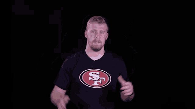 a man wearing a san francisco 49ers shirt is raising his hands in the air .