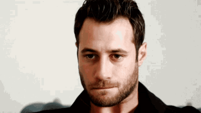 a close up of a man 's face with a beard and green eyes
