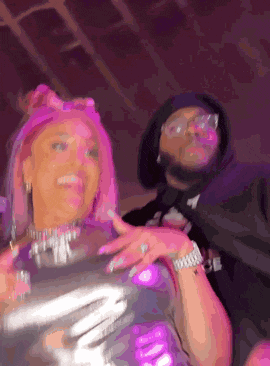 a man and a woman are standing next to each other in a room with purple lights .