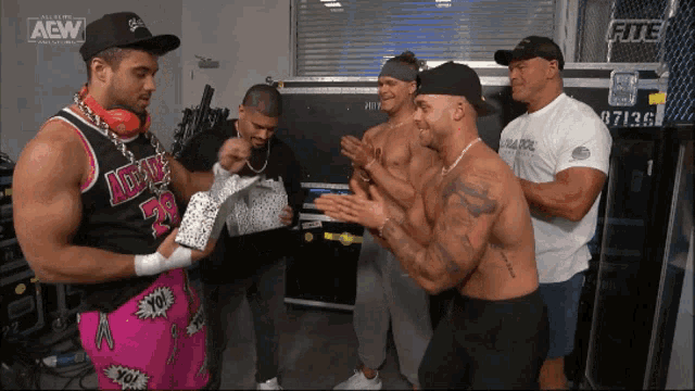 a group of wrestlers are standing in a room with a sign that says aew