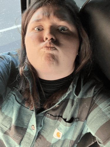 a woman wearing a plaid shirt with a carhartt logo