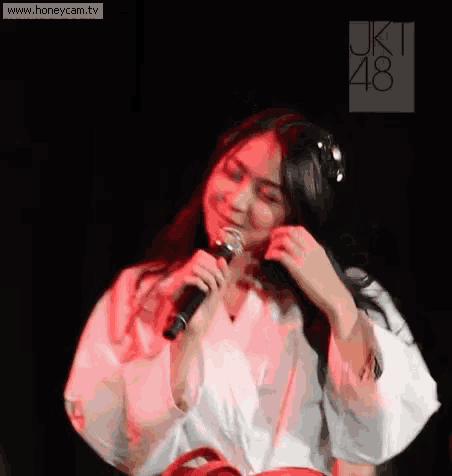 a woman in a white shirt is holding a microphone in her hand .