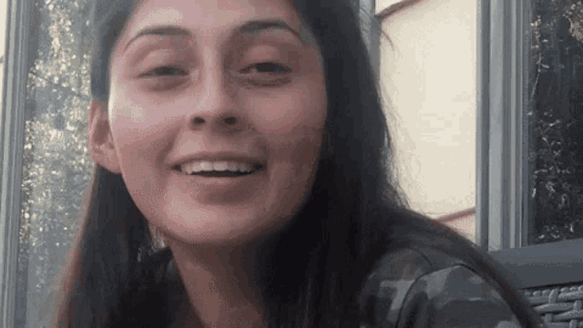 a woman wearing a camouflage shirt is smiling