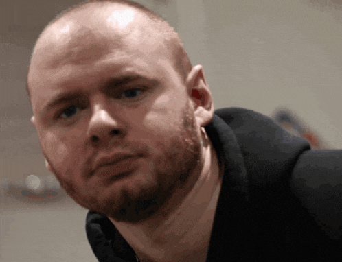 a bald man with a beard wearing a black hoodie