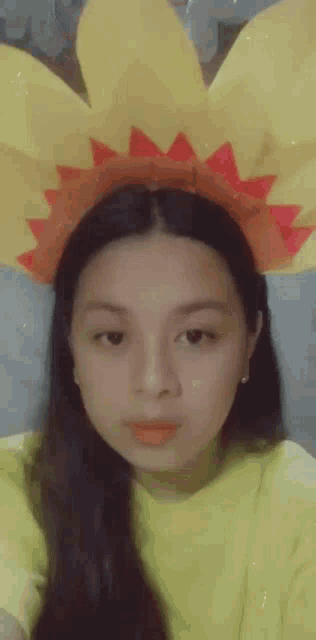 a young girl wearing a yellow shirt and a yellow flower headband
